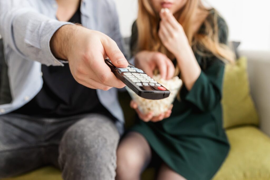 Paar sitzt auf dem Sofa und schaut Serien Beliebte Serien für den Filmabend zu zweit